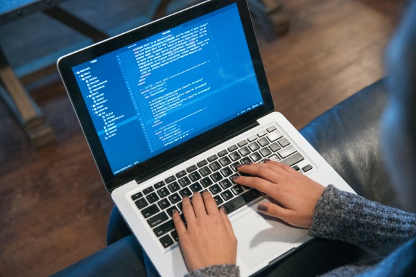 Hands Typing Code on Laptop